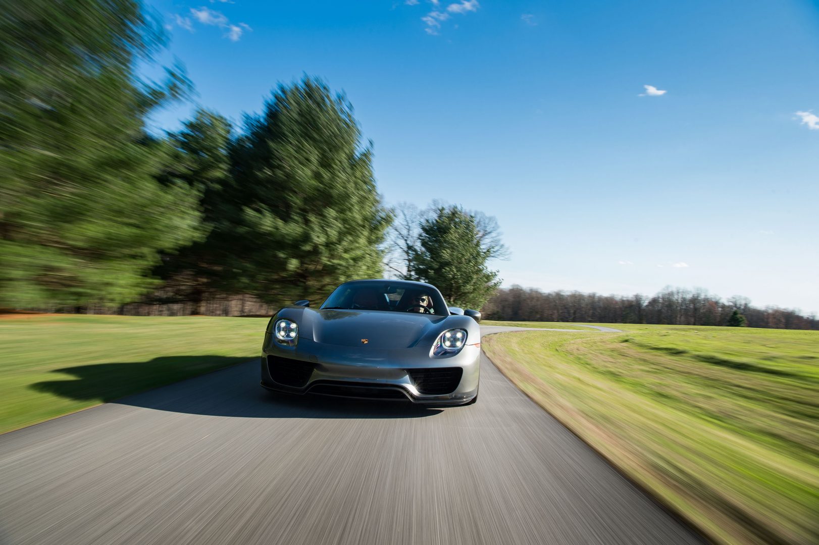 Silver Porsche 918 Spyder in motion front, blurred scenery; Porsche Finance