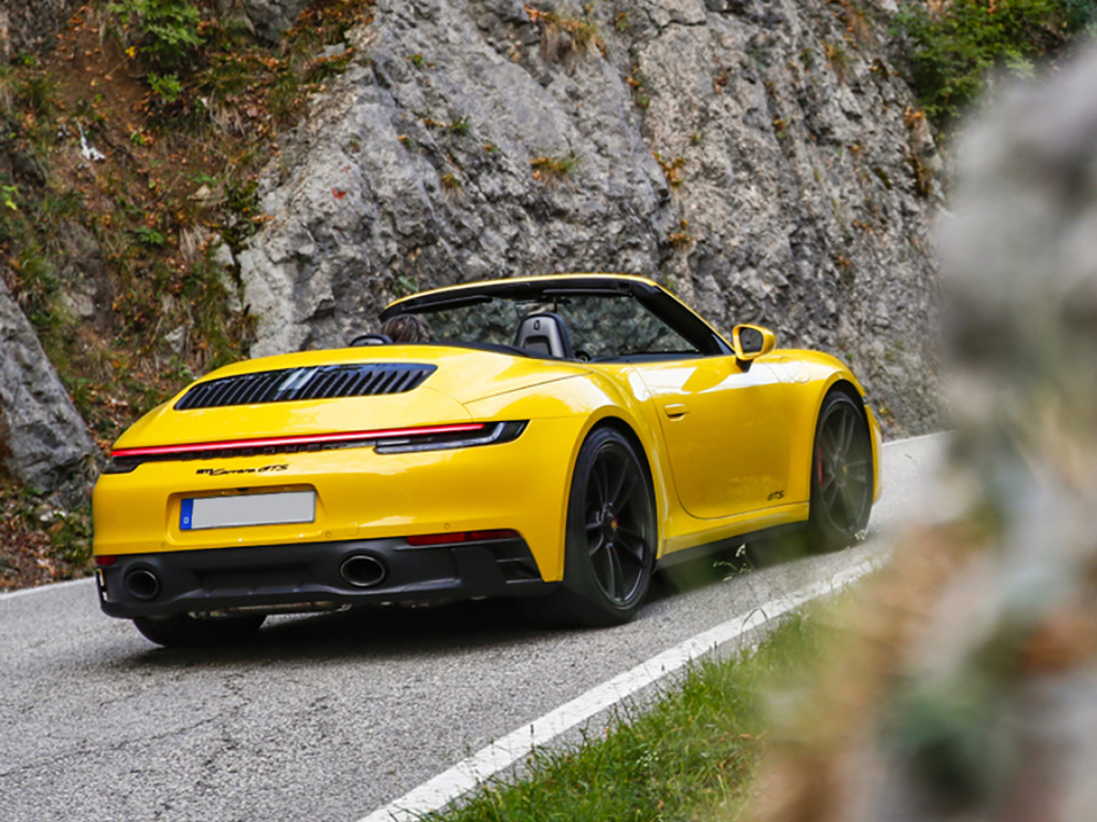 Yellow Porsche 911 Carrera GTS on road, rear view