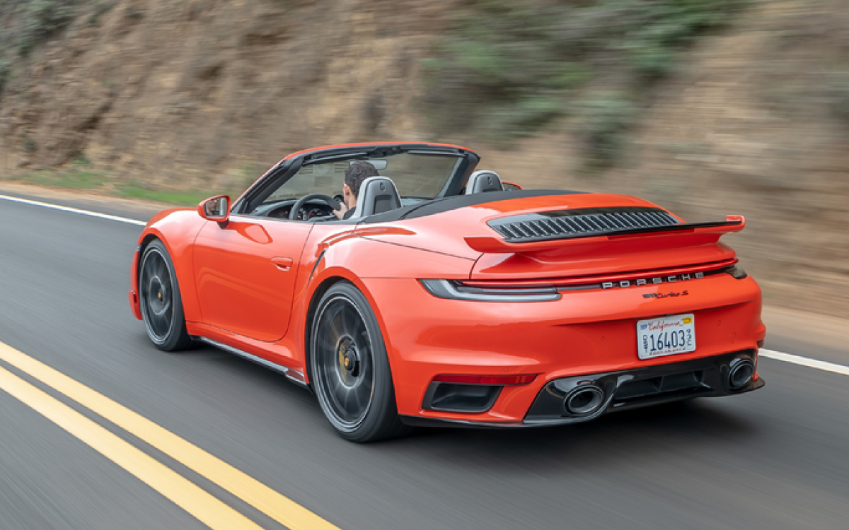 Orange Porsche 911 Turbo S Cabriolet on road, rear view